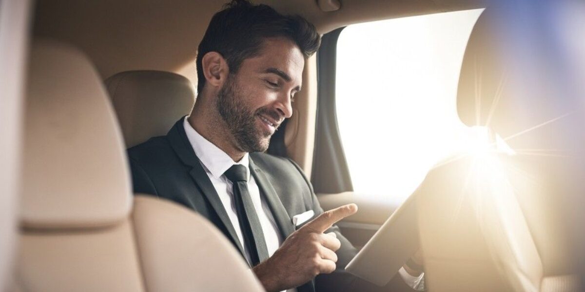 Businessman using phone in luxury car – HotWheelz corporate travel